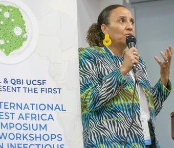 A person speaking in front of a banner stating: USL & QBI Present the first International West Africa Symposium and Workshops