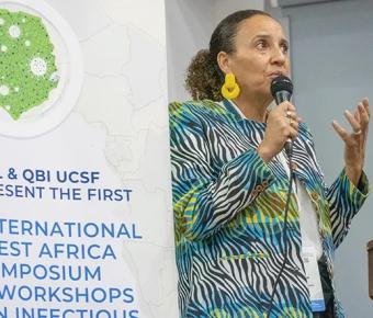 A person speaking in front of a banner stating: USL & QBI Present the first International West Africa Symposium and Workshops