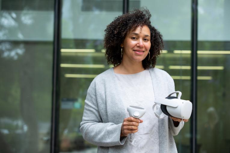 Nova Wilson of the CULTIVATE team holding the white VR headset and two hand controllers