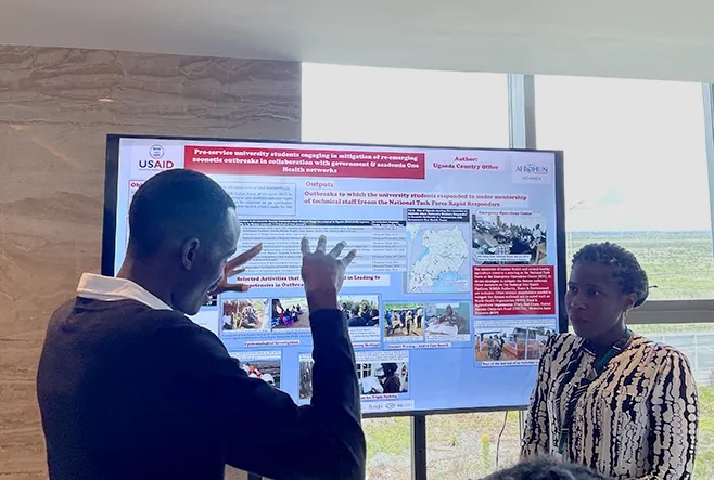 David Mugume (UCSF) and Angelia Musewa (AFROHUN Uganda) discuss response to zoonotic outbreaks at poster session.